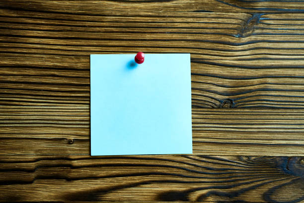 Blue sticker fixed with a red button on a wooden wall.