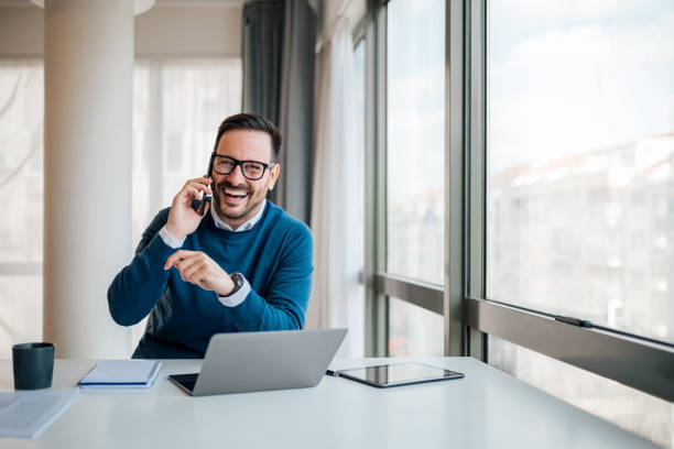 istock Happy professional discussing on cellphone while sitting at desk in office 1400210121