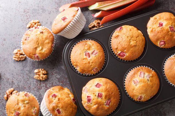 Homemade sweet muffins with rhubarb and walnuts close-up in a baking dish. horizontal top view Homemade sweet muffins with rhubarb and walnuts close-up in a baking dish on the table. horizontal top view from above walnut cookies stock pictures, royalty-free photos & images