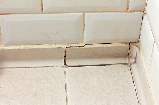 Damaged old joints between tiles in a bathroom shower. Ceramic tile grout repair