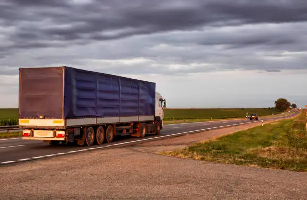 Photo of An overloaded truck transports cargo on an asphalt road. Axle load, transport inspection. Copy space for text