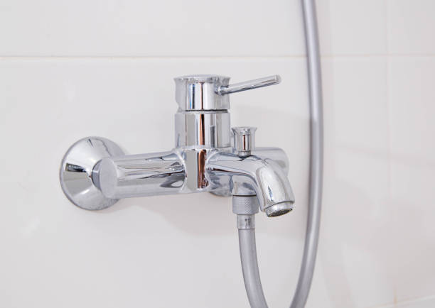 istock Modern silver chrome bathroom faucet with hot and cold water on a white wall. Close-up 1400211990