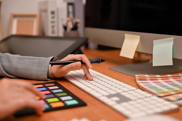 istock Female graphic designer holding a stylus one, typing on computer keyboard 1400215703