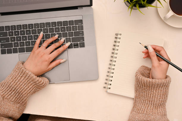 istock Female blogger working in her workspace, using a laptop computer and taking a list on diary. 1400215717