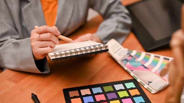 istock Female graphic designer taking lists on her spiral notepad at her office desk. 1400216622