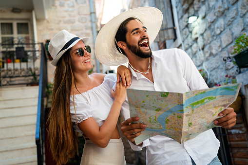 Happy tourists couple sightseeing city with map during summer vacation