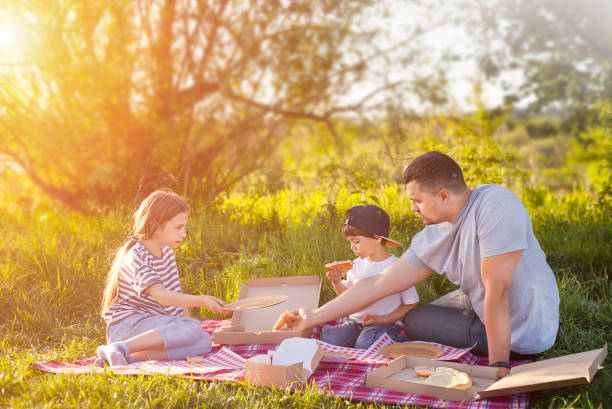istock father and two children sit outdoors on a picnic 1400222064