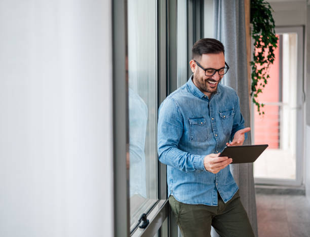 istock Cheerful businessman gesturing while using digital tablet by window at corporate office 1400224342