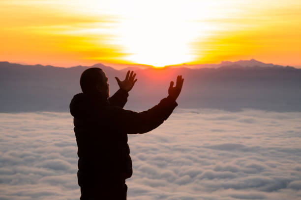 Man praying at sunrise mountains Travel Lifestyle spiritual relaxation emotional meditating concept vacations outdoor harmony with nature landscape
