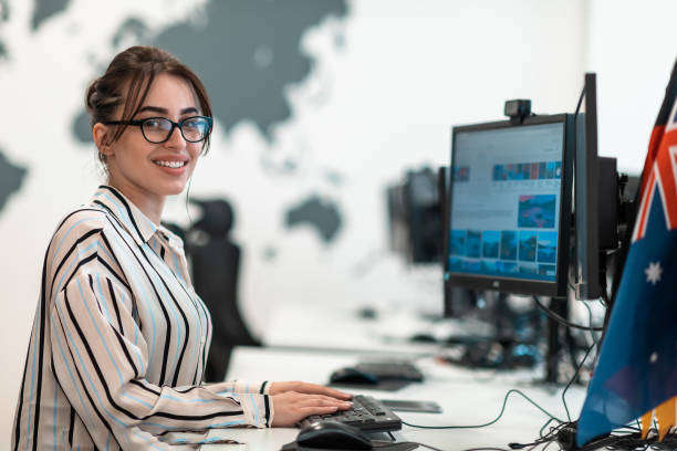 istock Casual business woman working on desktop computer in modern open plan startup office interior. Selective focus 1400224427