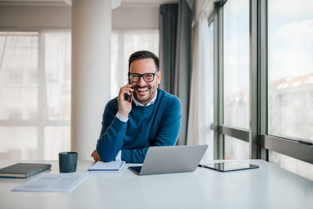 istock Cheerful entrepreneur talking on smart phone while working at desk in office 1400224445