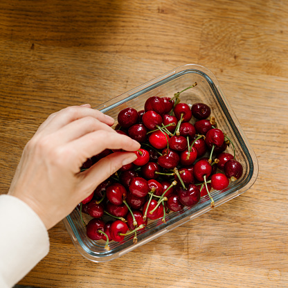 Cherries in a bowl ready to eat
Candid photo of real food and hand picking one