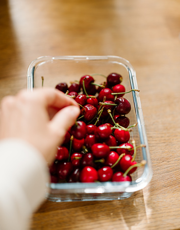 Cherries in a bowl ready to eat
Candid photo of real food and hand picking one