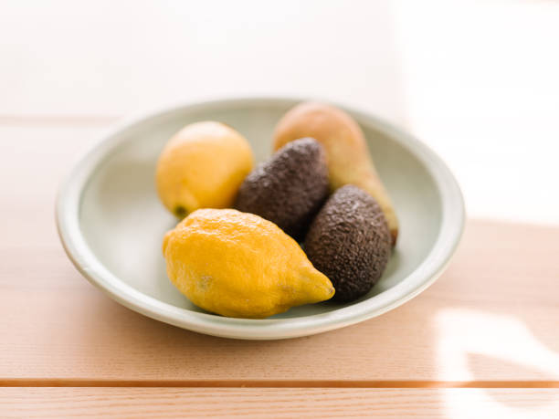 Some lemons and avocados in bowl on table