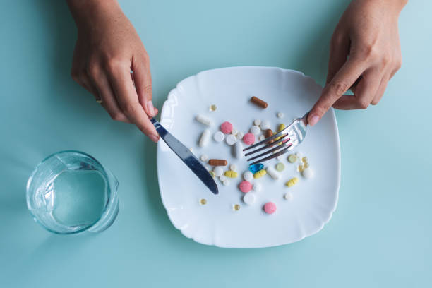 女性は丸薬や薬を食べています。健康食品、ダイエットの概念。 - nutritional supplement pill eating food ストックフォトと画像