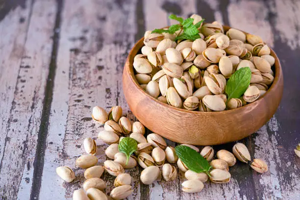 Pistachios in wooden bowl isolated on a wooden background