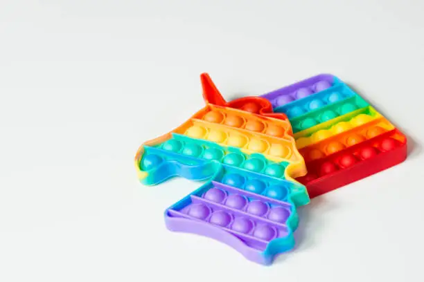 Photo of Colorful pop It game in the form of a unicorn on a white background. Anti-stress. Close-up of the popular children's toy pop It fidget.