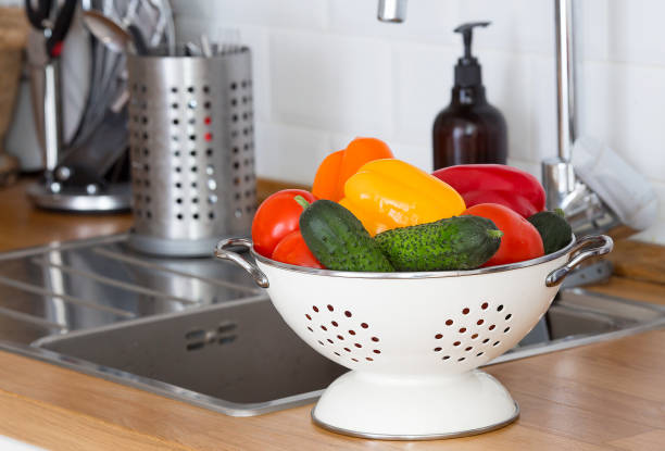 istock A man washes tomatoes, yellow bell peppers and other vegetables above a kitchen sink under running water to eliminate the possibility of COVID-19 contamination. 1400239396