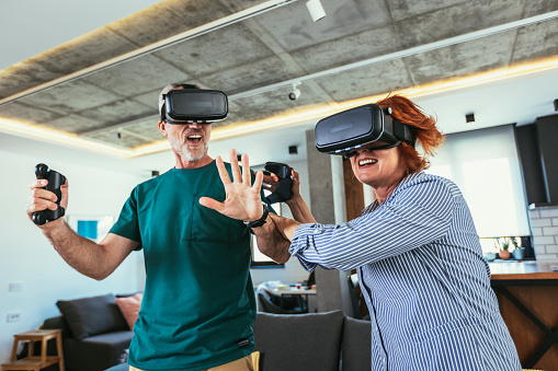 Group of middle age friends smiling happy playing video game with VR glasses at home.