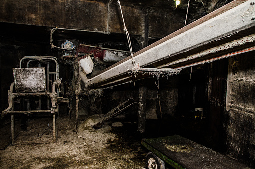 Dirty farm machinery in barn looking like horror movie set