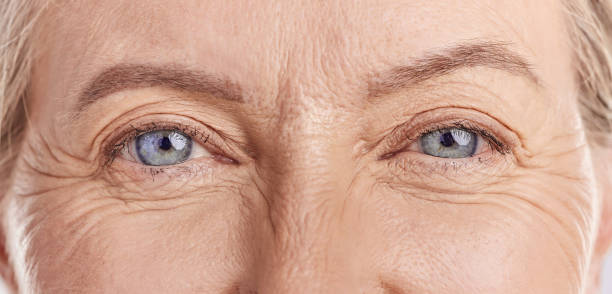 closeup portrait of a beautiful older woman's blue eyes. healthy and natural mature woman with deep lines and crows feet, feeling radiant and fresh while doing her daily beauty routine in a studio - wrinkles eyes imagens e fotografias de stock