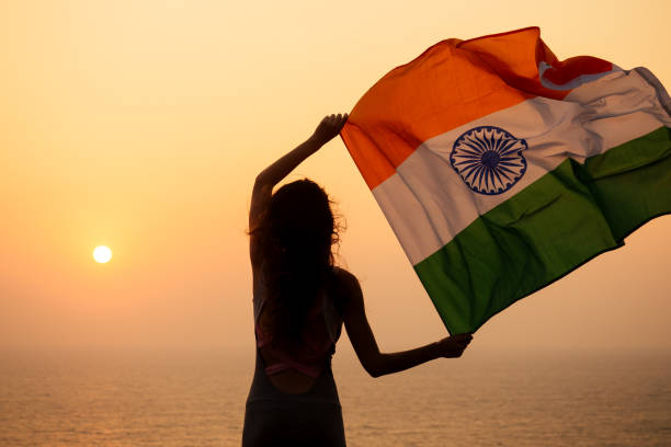 istock woman hjlding indian flag and looking at sunset 1400240909