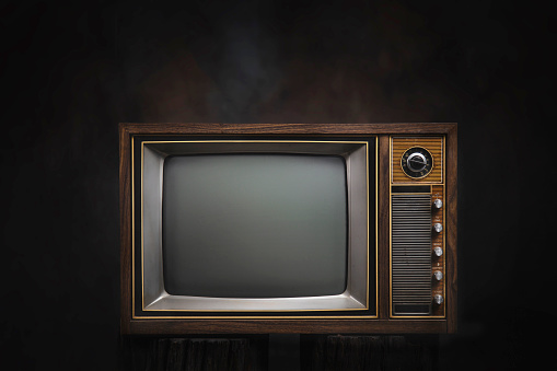 Retro old TV in dark room, black background.