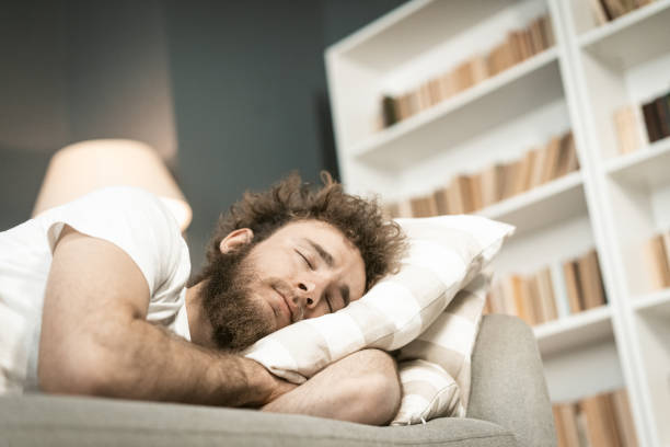 istock Sleeping on the sofa handsome bearded young man hugging a pillow after a long hours working late nigh. Sick young man sleeping on the couch after taking medications. distance work concept 1400244665
