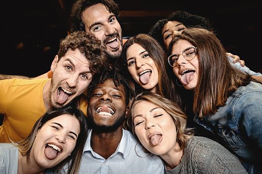 Portrait of happy friends embracing and making grimaces looking at the camera - people having fun, diversity, inclusion and integration lifestyle concept