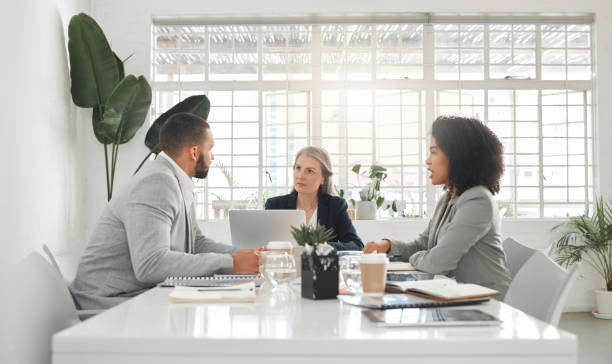 istock Three businesspeople having a meeting together at a table at work. Business professionals talking and planning in an office. Mature caucasian boss talking to her employees 1400247986
