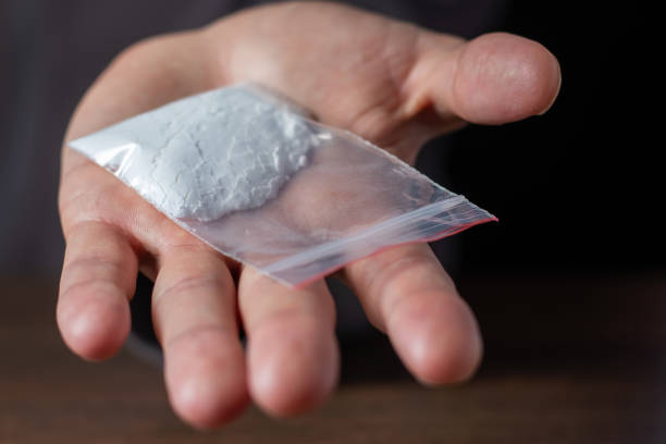 Man hand holds plastic packet or bag with cocaine or another drugs, drug abuse and danger addiction concept Man hand holds plastic packet or bag with cocaine or another drugs, drug abuse and danger addiction concept. wrongful death stock pictures, royalty-free photos & images