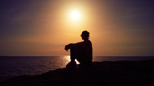 istock Silhouette of a woman watching sunset over distant horizon. 1400255279