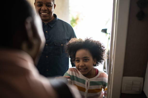 istock Father and daughter being greeted by real estate agent (or mother opening the front door to his daughter and husband) 1400256678