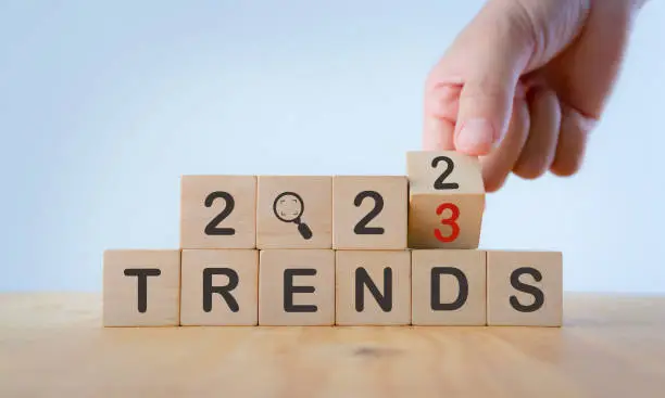 Photo of 2023 trend concept. Hand flip wooden cube change year 2022 to 2023. Beautiful white background, copy space. Used for the banner trend concept of the new year for monitoring new business opportunities.