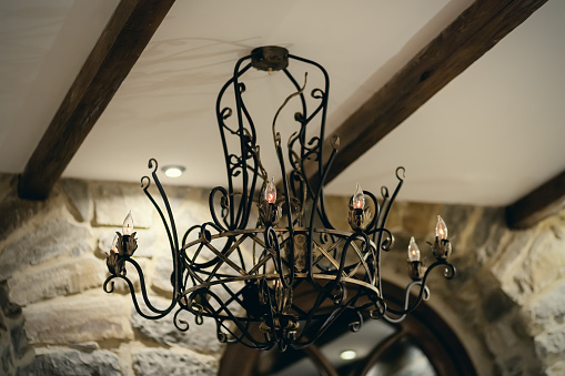A wrought iron chandelier hangs in a medieval-styled interior. Soft focus.