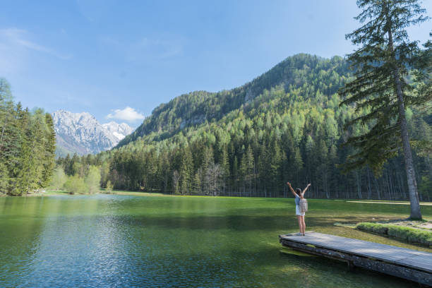istock Young woman relaxes on forested lakeside dock 1400261165