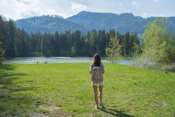 She looks off towards distant scene, on a summer morning