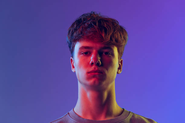 istock Young red-headed man, student isolated over blue studio background in neon light. Concept of youth, fashion, emotions, facial expression 1400262353