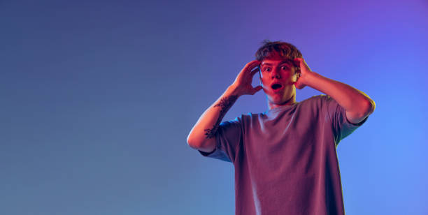 istock Shocked young red-headed man, student isolated over blue studio background in neon light. Concept of youth, fashion, emotions, facial expression 1400262354