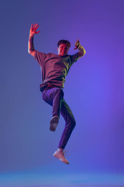 istock Young red-headed man, student isolated over blue studio background in neon light. Concept of youth, fashion, emotions, facial expression 1400262355
