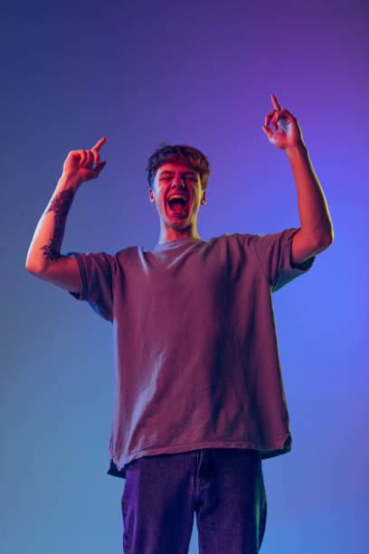 istock Young red-headed man, student isolated over blue studio background in neon light. Concept of youth, fashion, emotions, facial expression 1400262357