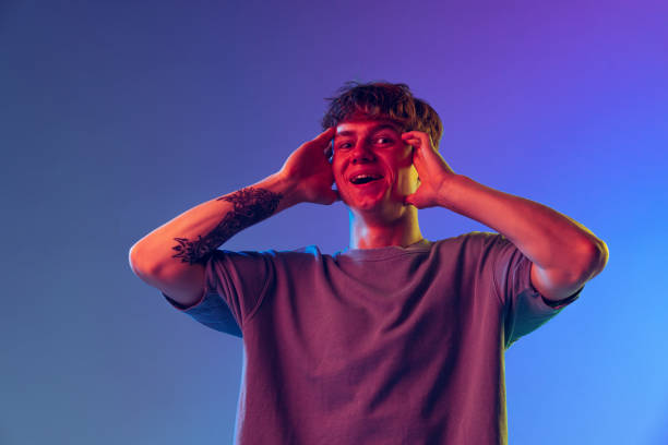 istock Young red-headed man, student isolated over blue studio background in neon light. Concept of youth, fashion, emotions, facial expression 1400262362