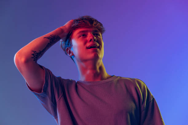 istock Young red-headed man, student isolated over blue studio background in neon light. Concept of youth, fashion, emotions, facial expression 1400262363