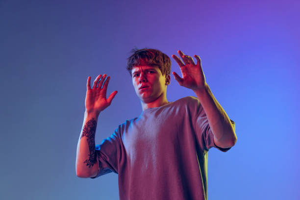 istock Young red-headed man, student isolated over blue studio background in neon light. Concept of youth, fashion, emotions, facial expression 1400262364