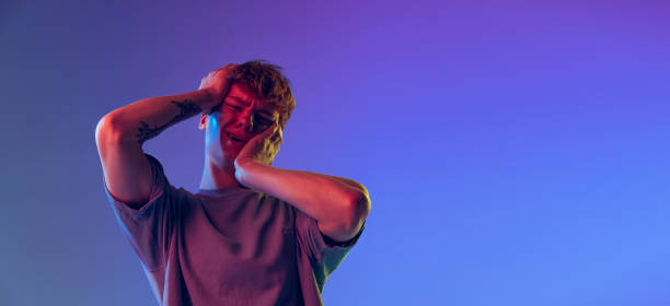 istock Young red-headed man, student isolated over blue studio background in neon light. Concept of youth, fashion, emotions, facial expression 1400262371