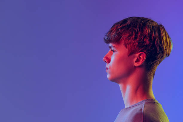 istock Profile view young red-headed man, student isolated over blue studio background in neon light. Concept of youth, fashion, emotions, facial expression 1400262374