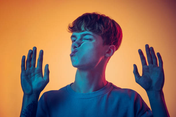 Young handsome man, student leaned against transparent glass isolated on yellow background. Close-up. Concept of human emotions Grimace. Young handsome man, student leaned against transparent glass isolated on dark studio background. Close-up. Concept of human emotions, facial expression, music, ad, fashion, beauty. crushed stock pictures, royalty-free photos & images