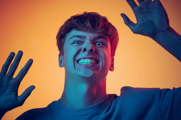 istock Young handsome man, student leaned against transparent glass isolated on yellow background. Close-up. Concept of human emotions 1400262384