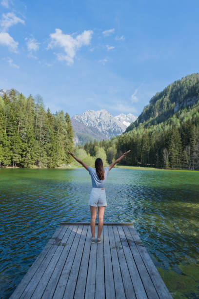 istock Young woman relaxes on forested lakeside dock 1400262433