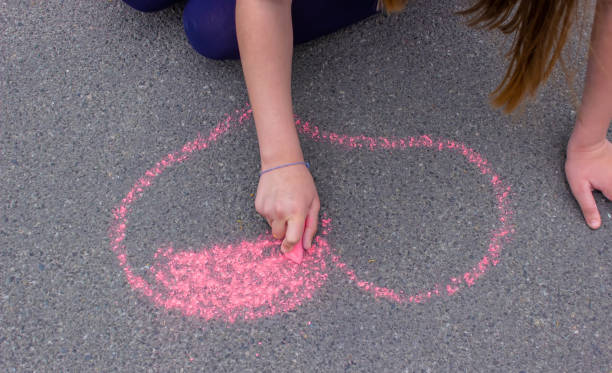 istock child's hand draws hearts, drawings chalk on asphalt 1400263063